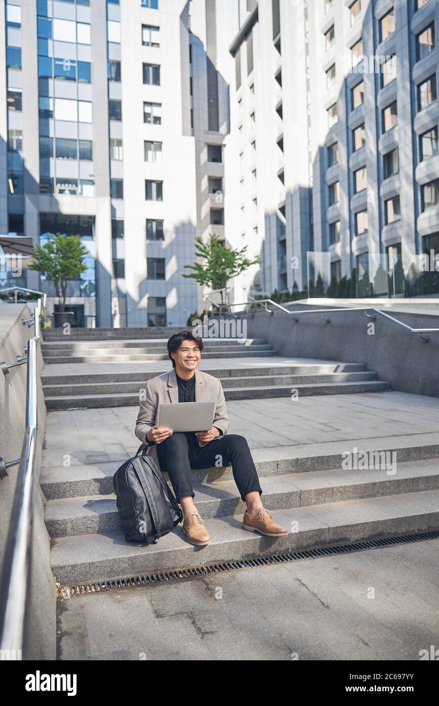 Joyful young man using notebook on the street Stock Photo