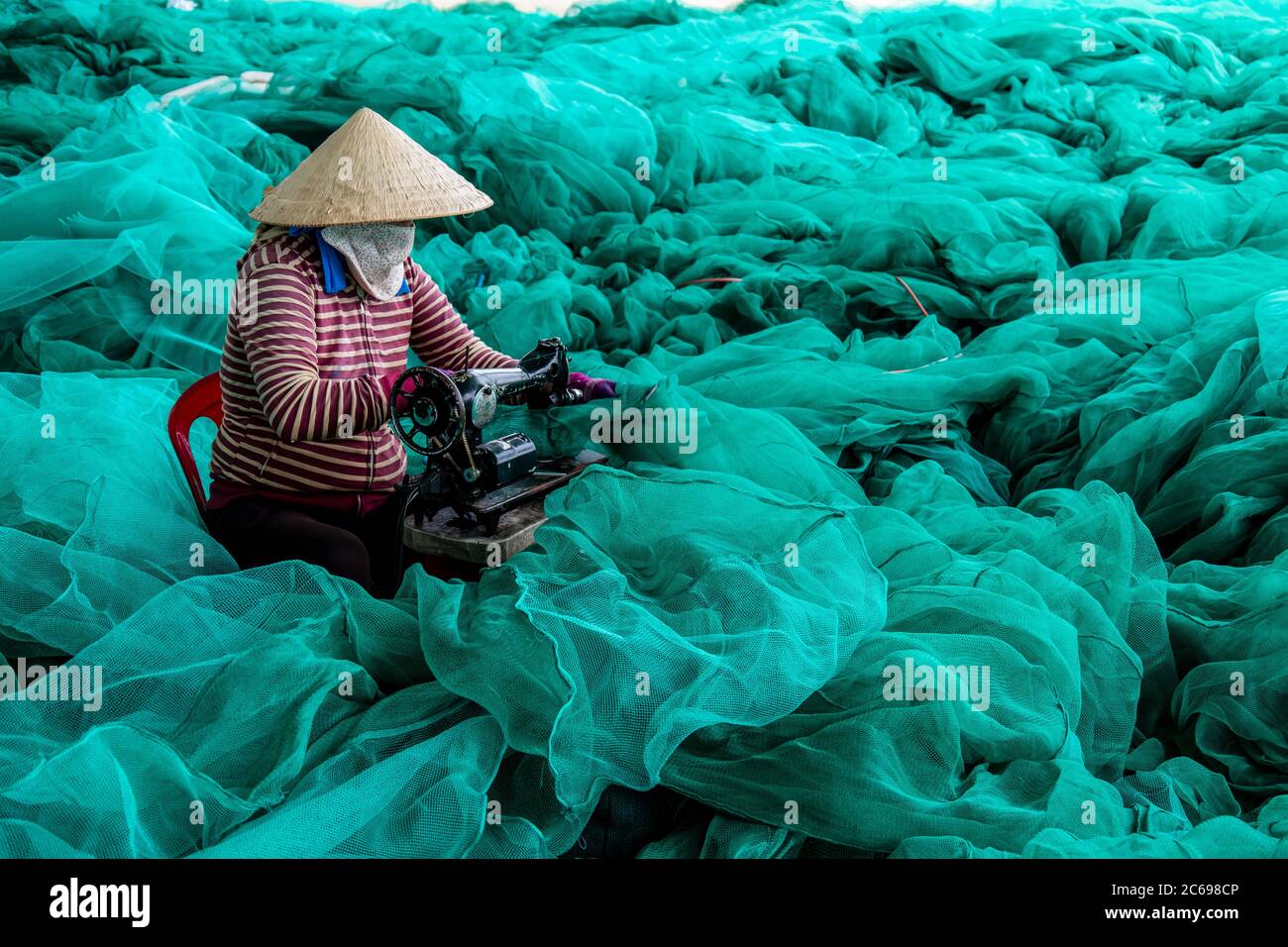 Woman repairing fishing nets, Vietnam Stock Photo