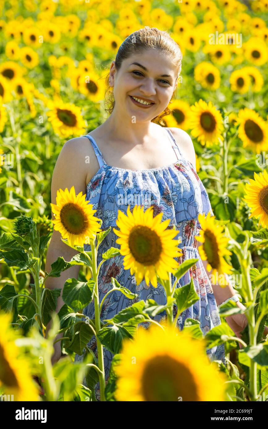 Happy woman in blue dress in sunflower field Stock Photo - Alamy