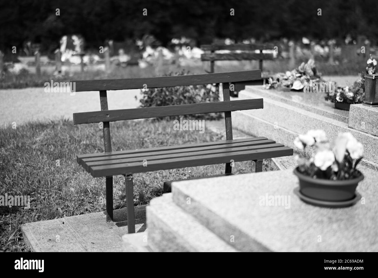 KOSICE, SLOVAKIA, 4 AUGUST 2019: A vivid red bench in front of a tomb covered by concrete block on local cemetery; very shallow depth of field. Stock Photo