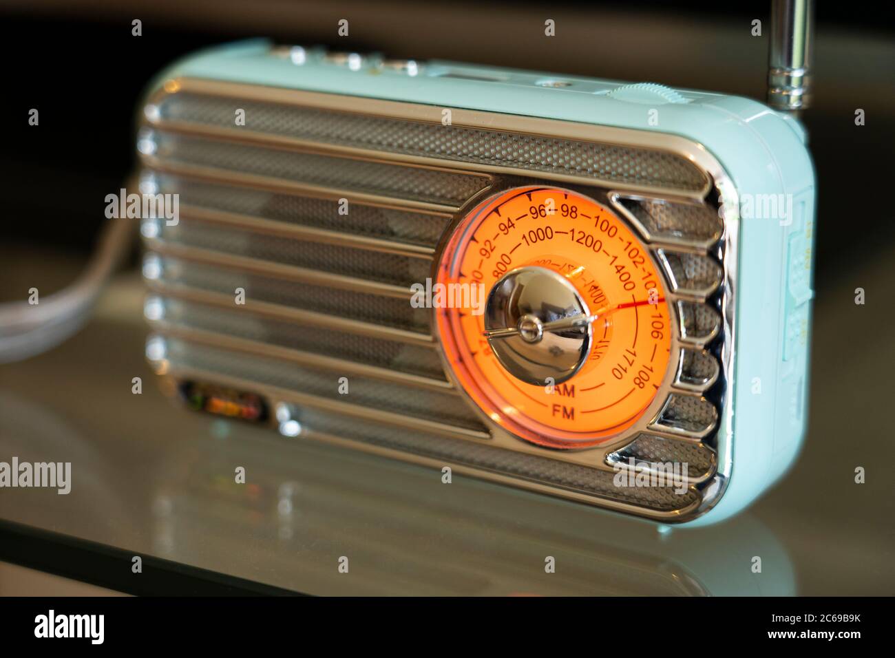 A blue portable pocket retro bluetooth radio with an illuminated orange FM / AM dial in a household lounge, UK Stock Photo