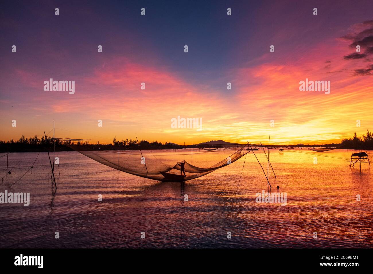 Silhouette of a fisherman checking his nets at sunrise, Vietnam Stock Photo