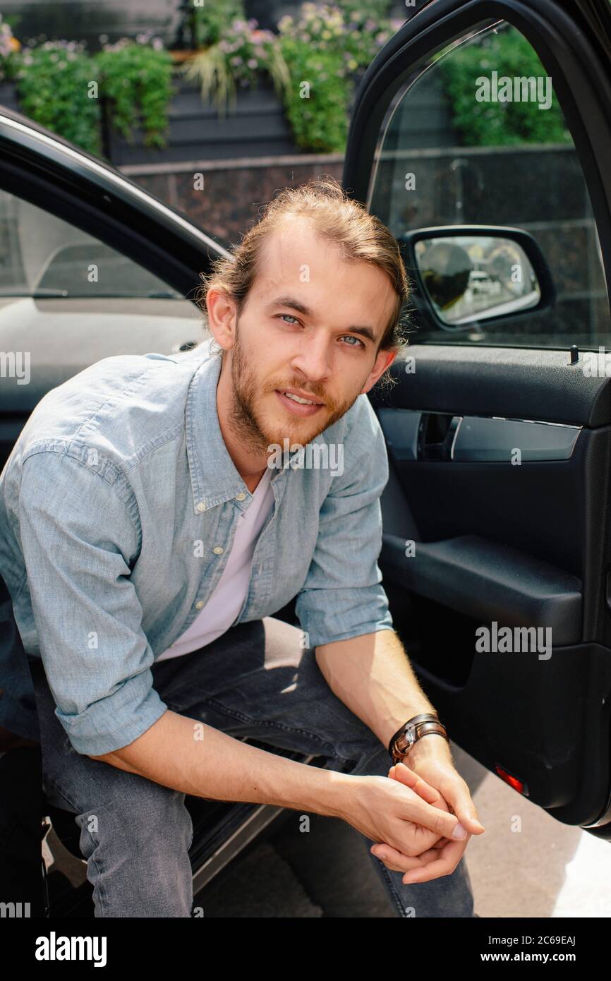 Portrait of a man sitting in a car with the door open Stock Photo