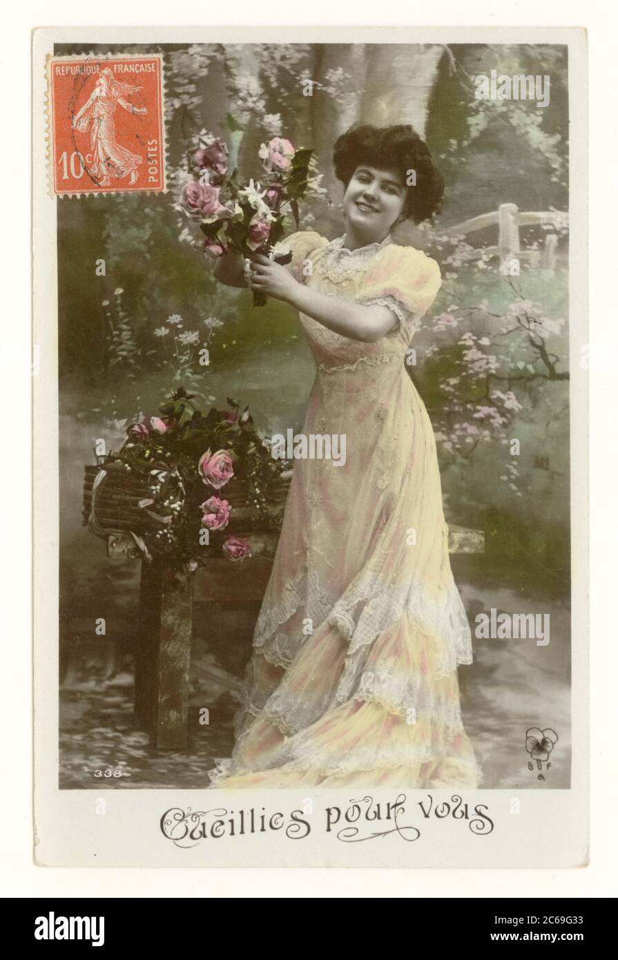 Early 1900's French sentimental tinted greetings postcard of a pretty woman in long flowing dress smiling and picking roses  - entitled 'Picked for you', France, circa 1911 Stock Photo