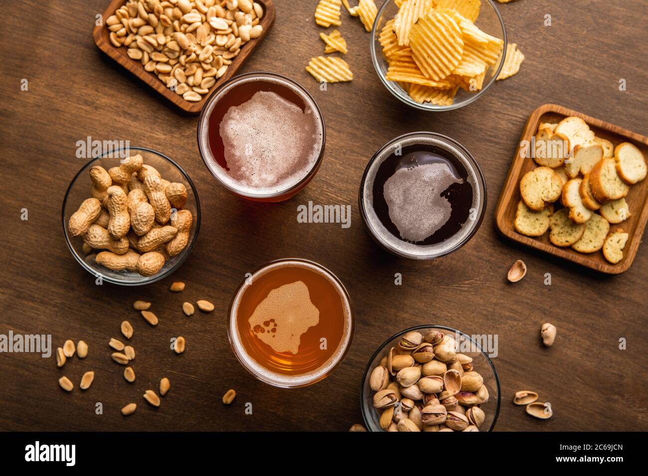 Client service in pub. Dark, light, unfiltered beer in glasses, nuts and chips in plates Stock Photo