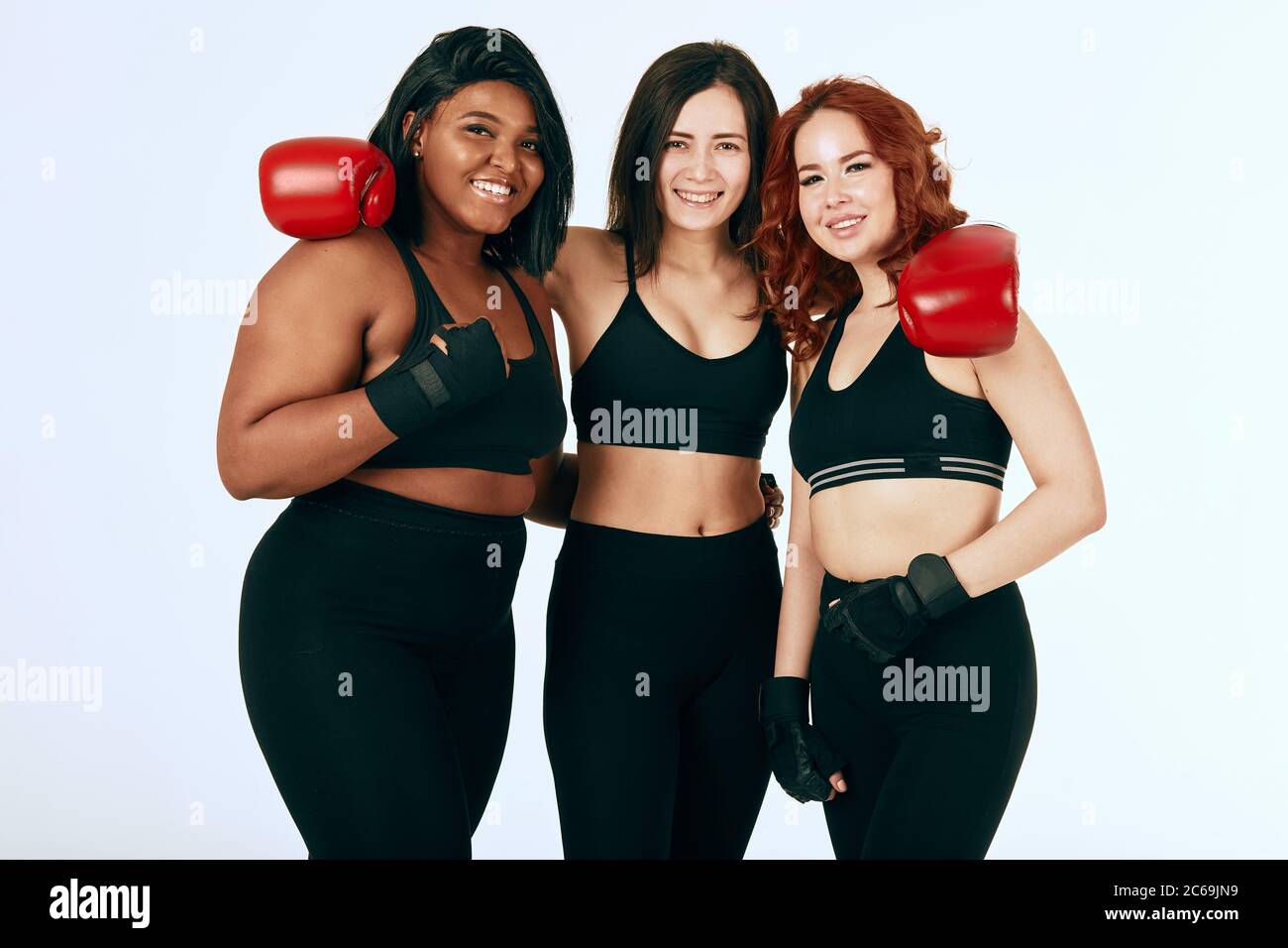 Group of three female boxers posing together in sportswear and red boxing  gloves against white background. Multiracial females with different size  sta Stock Photo - Alamy