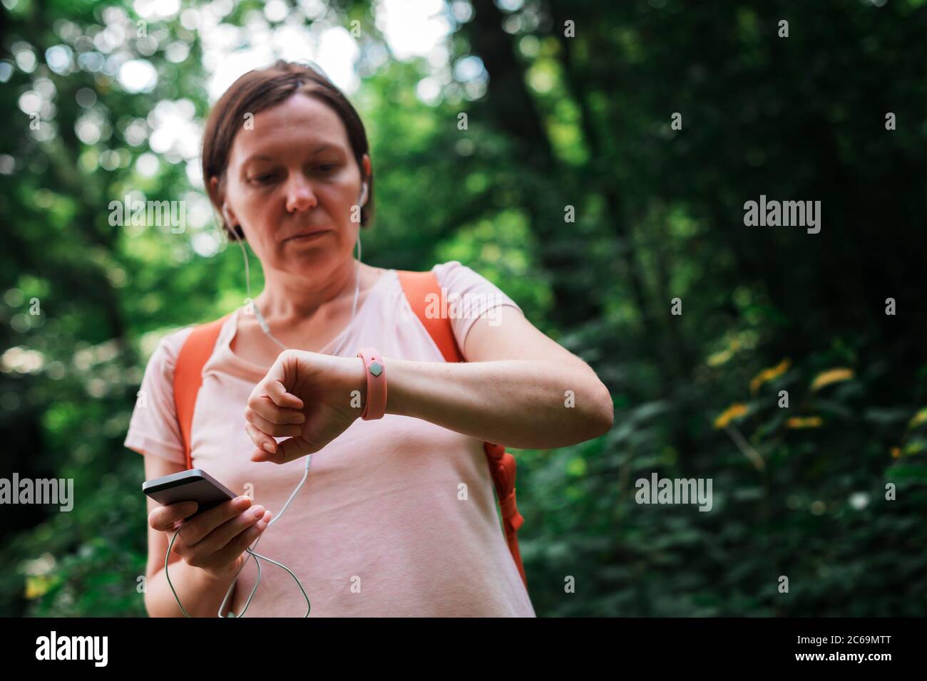 Female hiker checking fitness tracker wristband data and synchronizing