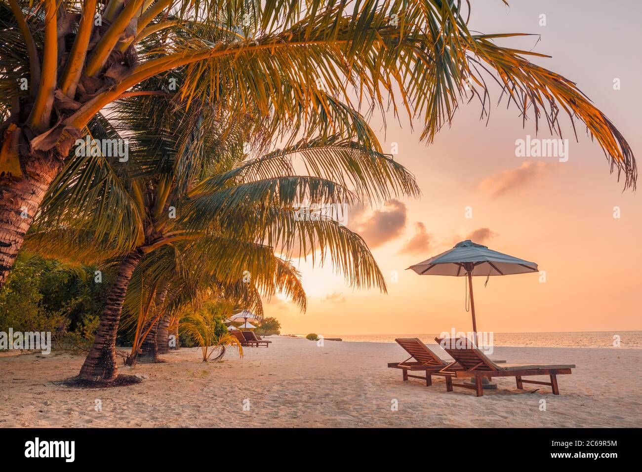 Beautiful tropical sunset scenery, two sun beds loungers umbrella palm ...