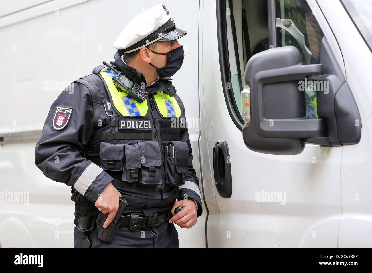 Hamburg, Germany. 24th Apr, 2020. A policeman is on duty at a police  control in Max-Brauer-Allee. He is holding a hand on his service weapon.  Hamburg police checked drivers in the Altona