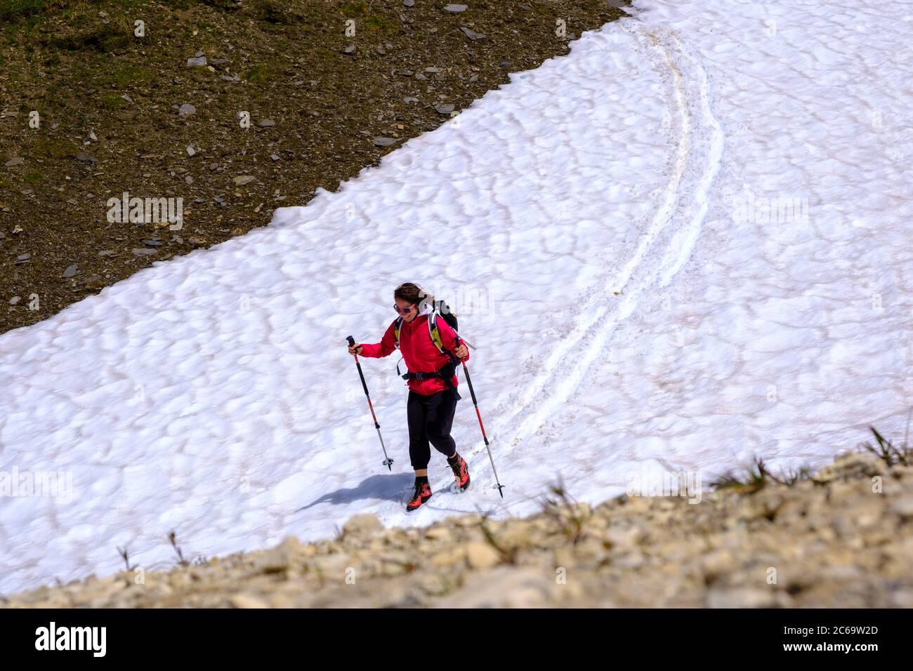 A girl has fun sliding on snow in summer. Nufenenpass, Switzerland Stock Photo