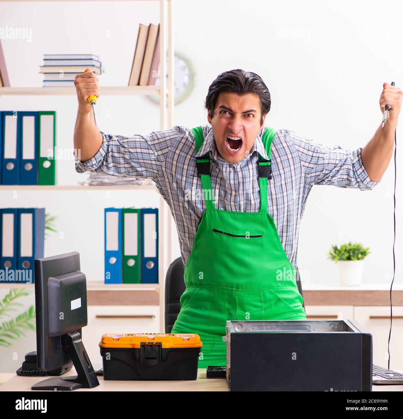 The young engineer repairing broken computer at the office Stock Photo ...