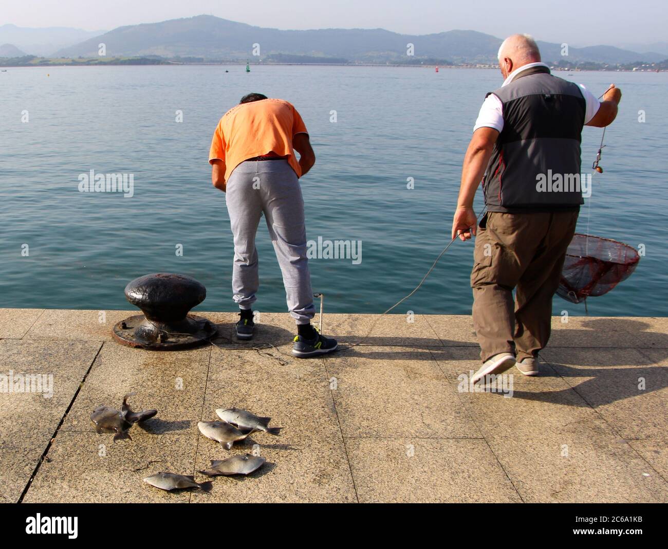 Two fishermen with caught Grey triggerfish Balistes capriscus Early morning fishing with rod and line in the bay of Santander Cantabria Spain Stock Photo