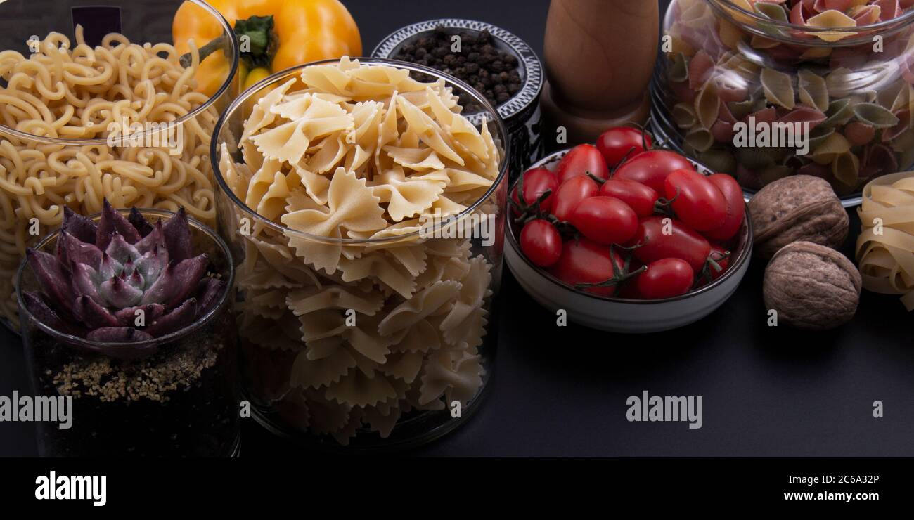 Colorful and colorful pasta in large numbers and different colors together with different fruits and vegetables. Stock Photo