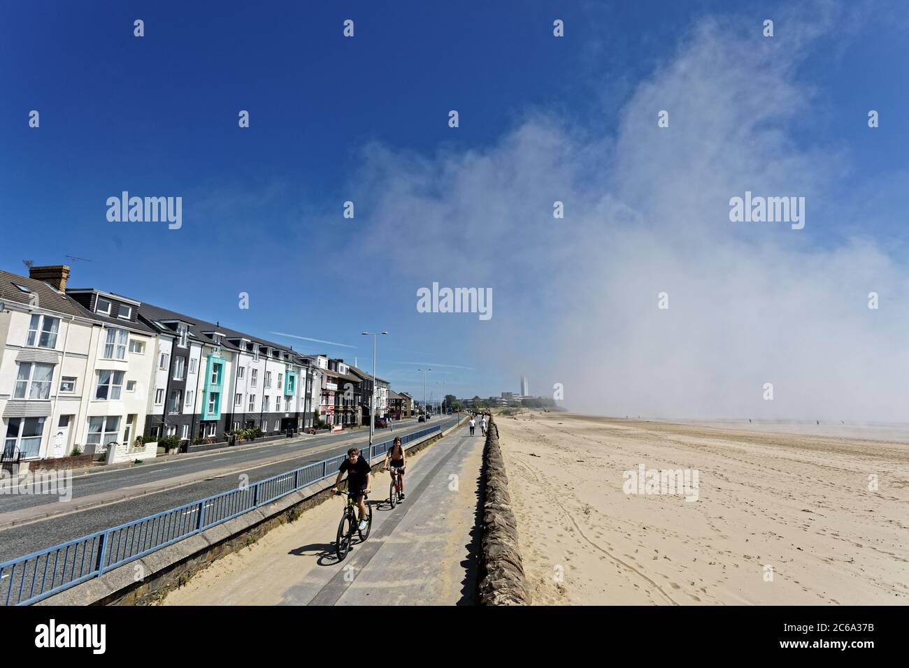 Pictured: The low cloud seen over the beach, whereas houses across the road are exposed to the sun in Swansea Bay, Wales, UK. Wednesday 20 May 2020 Re Stock Photo