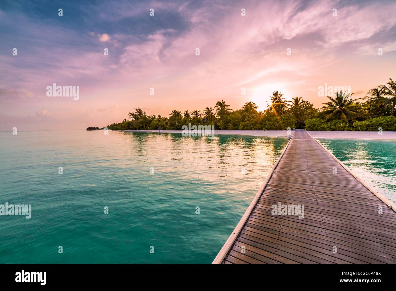 Sunset on Maldives island, luxury water villas resort and wooden pier, palm tree beautiful sky and clouds beach background for summer vacation holiday Stock Photo