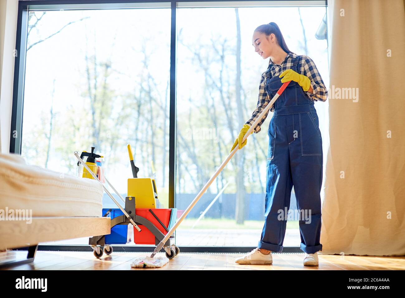 Attractive caucasian female cleaner mopping floor using detergents