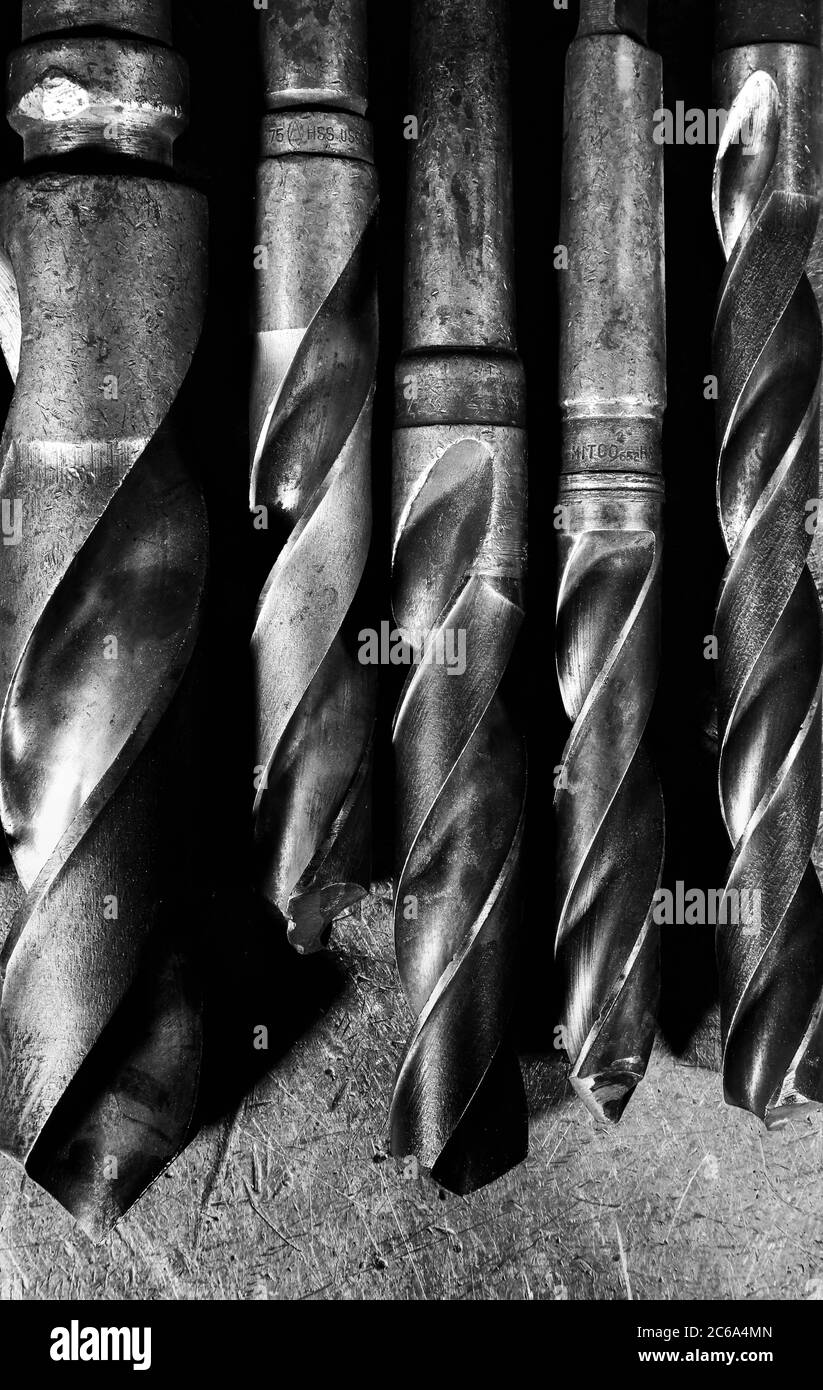 Industrial tools such as screws and nails and drills are halved or intertwined in the black and white image. Stock Photo