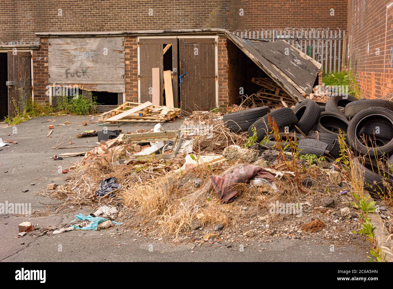 Old garages with rubbish flytipped in front of them Stock Photo Alamy
