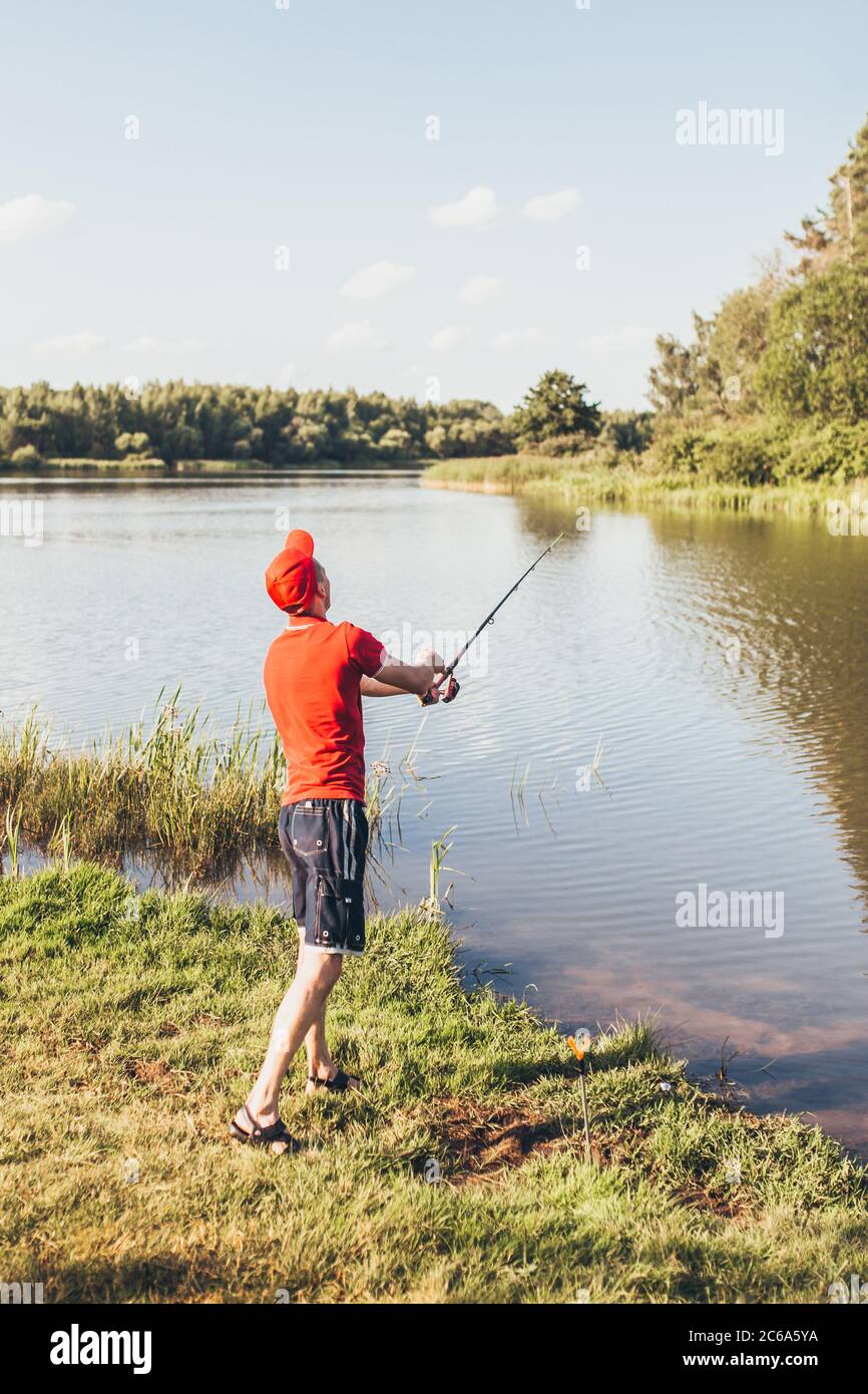 amateur fishing pole Fisherman on the bank throws a fishing rod into the river - amateur fishing  in fresh water Stock Photo