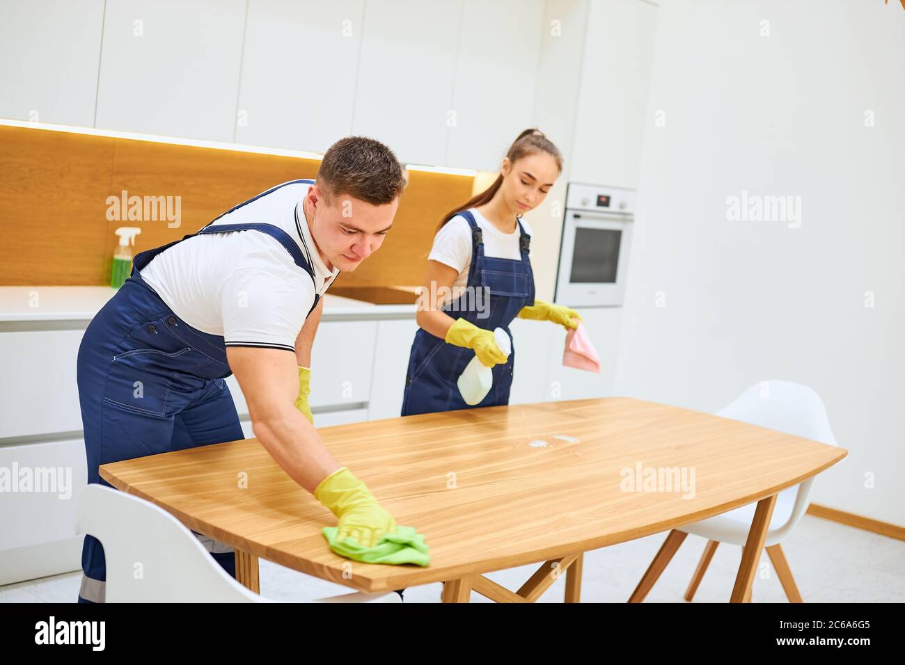 Two young cleaners in uniform effectively and quickly work together in
