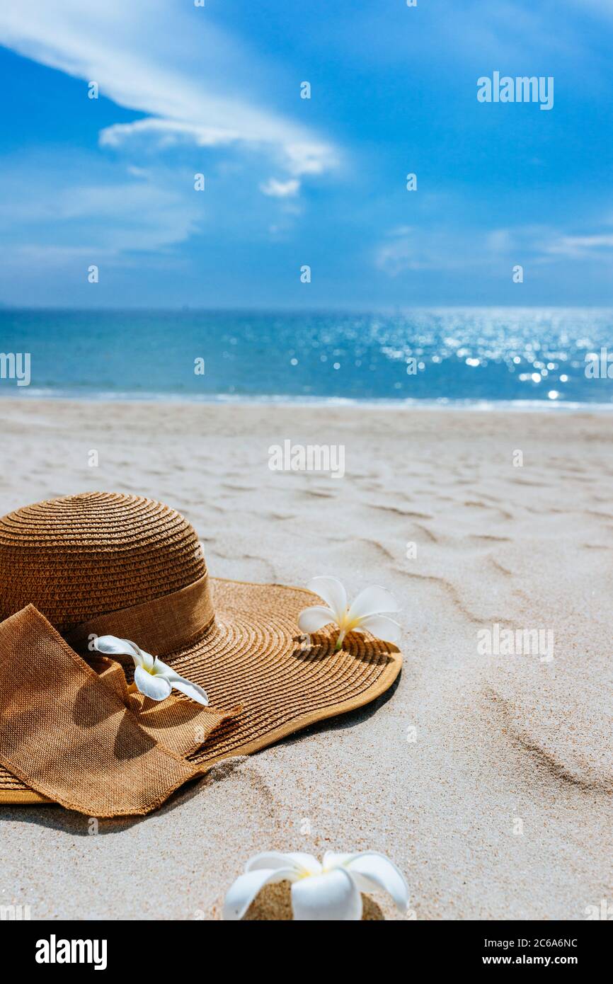 https://c8.alamy.com/comp/2C6A6NC/straw-hat-with-frangipani-flowers-on-white-sea-sand-with-beautiful-seascape-the-blue-sea-in-the-background-background-for-advertisement-of-a-seasid-2C6A6NC.jpg