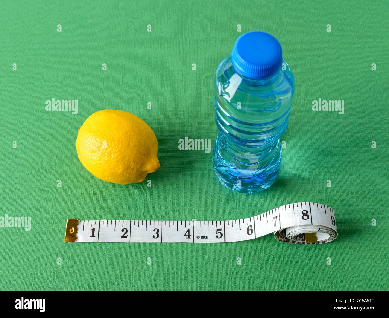 Inch measuring tape, ripe lemon and bottle of pure drinking water on a