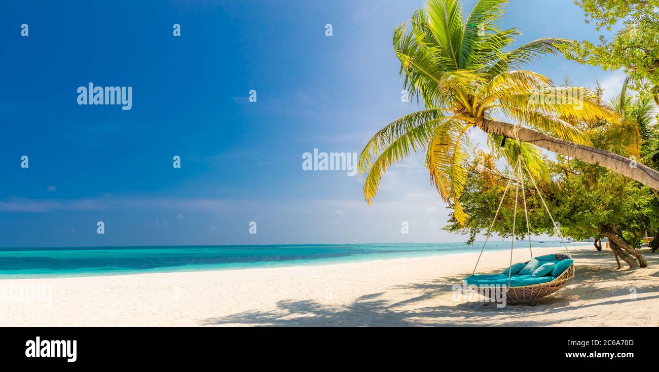 Tropical beach panorama as summer landscape with beach swing or hammock and white sand and calm sea for beach banner. Perfect beach scene vacation Stock Photo