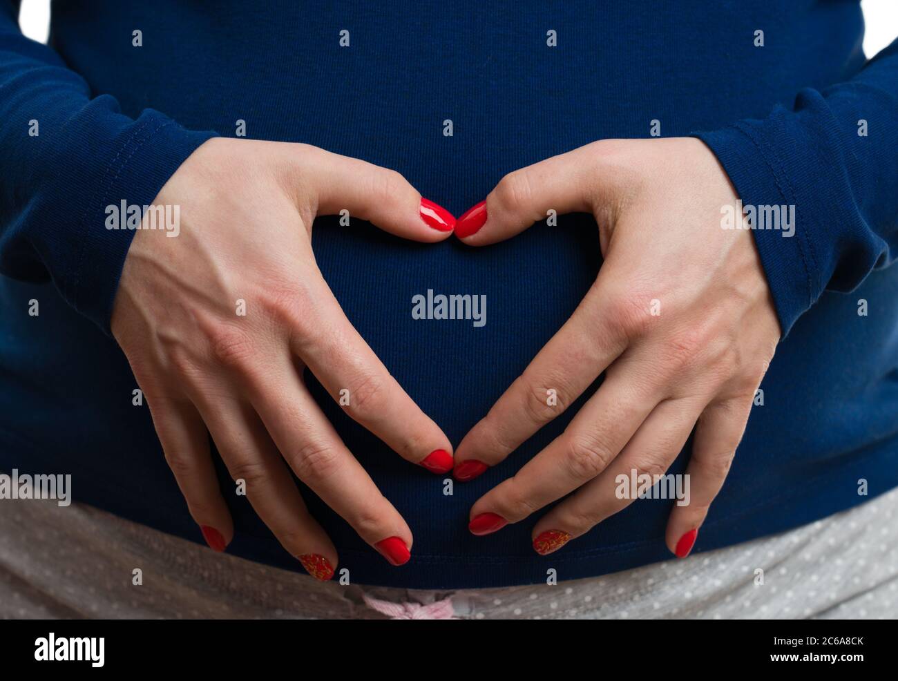 Closeup of pregnant woman making heart gesture on abdomen as love concept isolated on white background Stock Photo