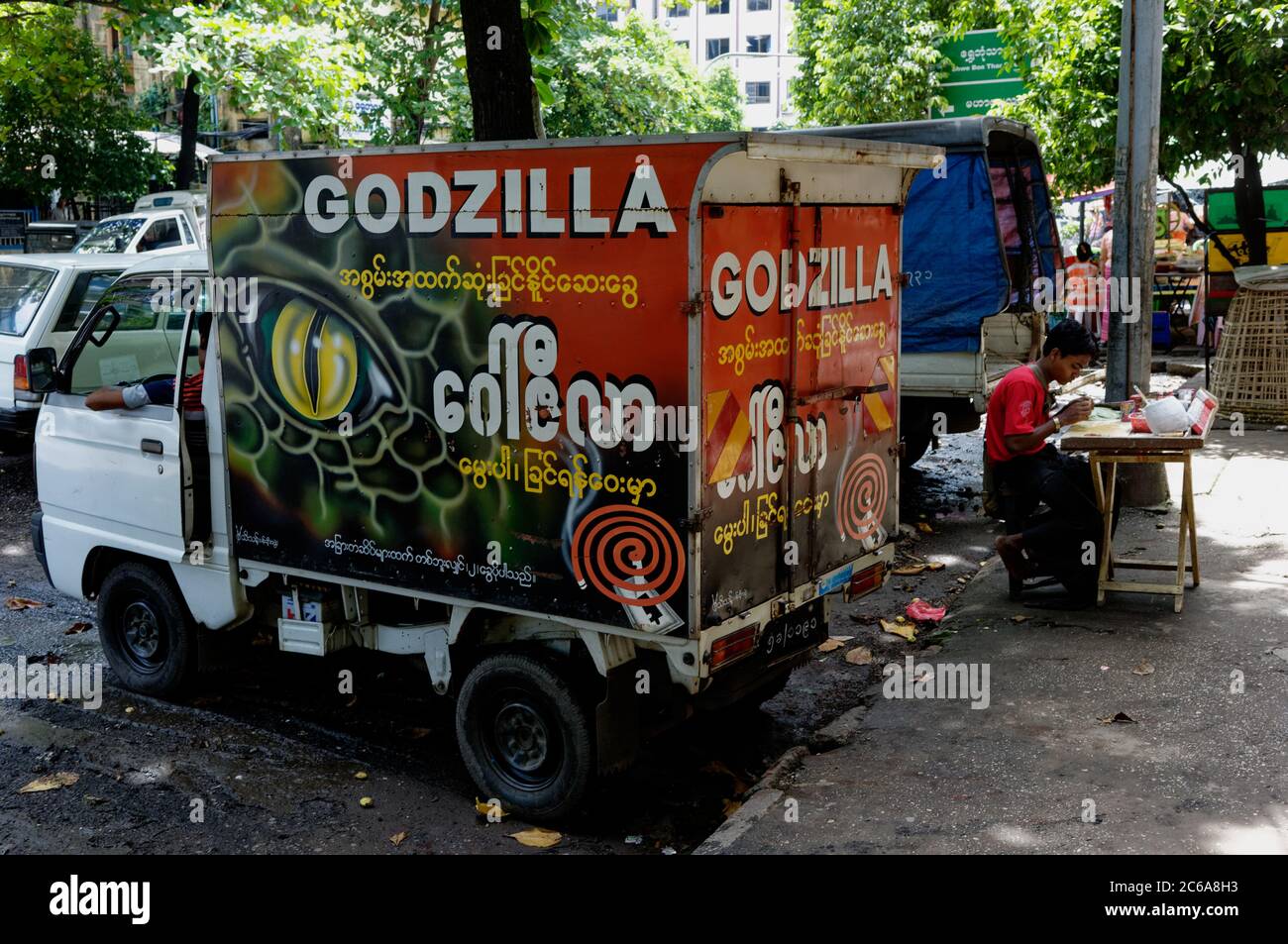 Godzilla delivery mini van near a hawker stall on the streets of Yangon, Myanmar. Asia Stock Photo