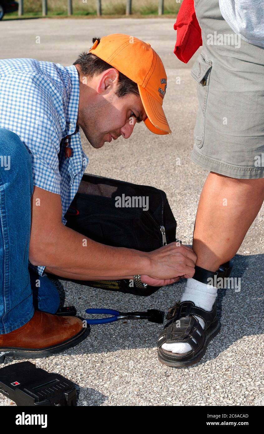 Austin, Texas USA, 2003: Texas parole officer attaches electronic monitoring device to a parolee's ankle. ©Bob Daemmrich Stock Photo