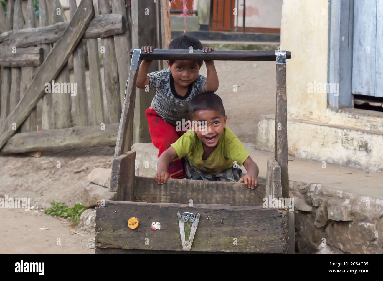 A couple of kids, belonging to the Khasi tribe from Meghalaya, India, playing with a wooden cart outside of their house. Stock Photo