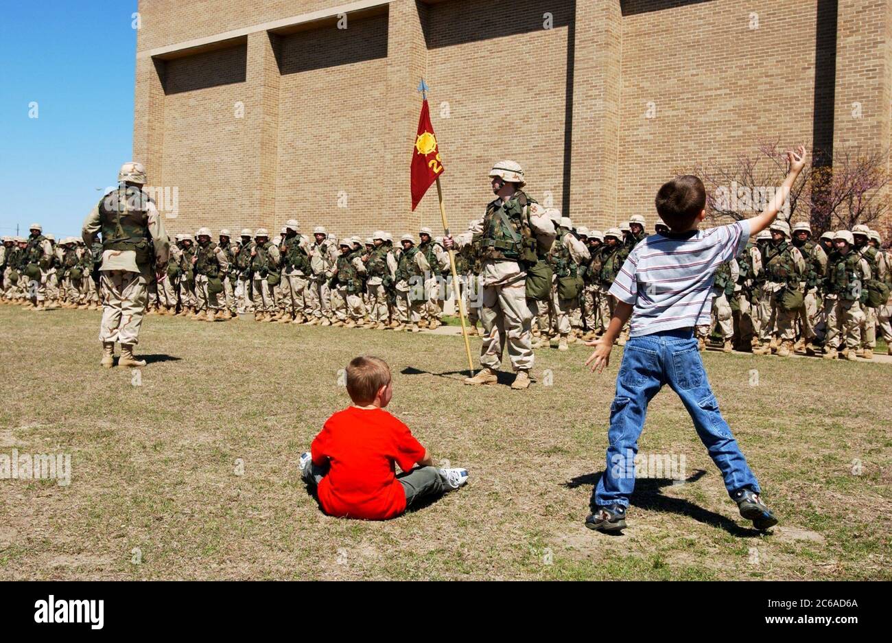 Fort Hood, Texas USA, March 23, 2003: Boys play in the grass as U.S. Army troops of the III Corps 13th Corps Support Command (COSCOM) based at Fort Hood prepare to leave Texas after receiving deployment orders two days earlier. The troops will provide logistical and medical support to fighting units based in the Persian Gulf.  ©Bob Daemmrich Stock Photo