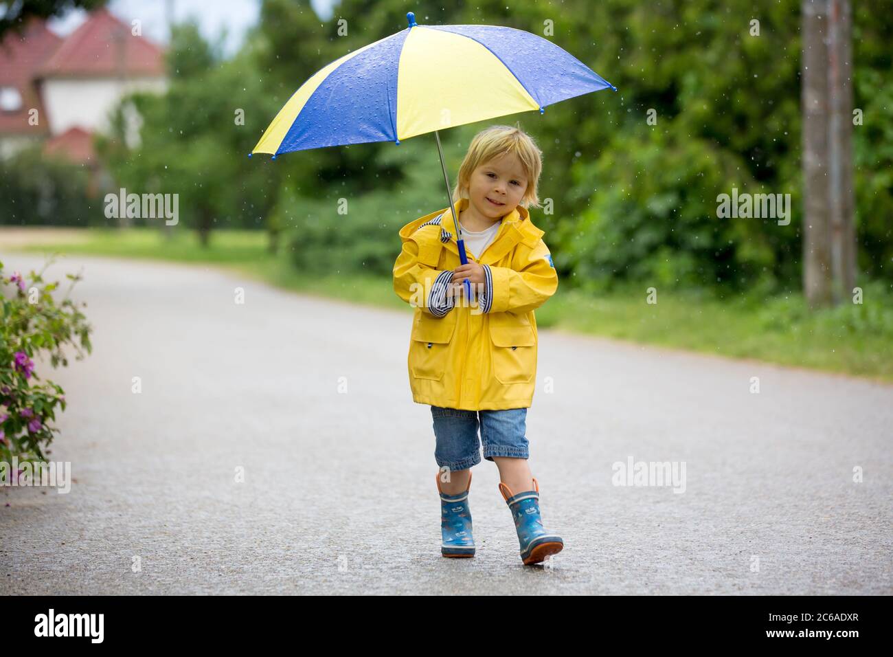 Mother and toddler child, boy, playing in the rain, wearing boots and