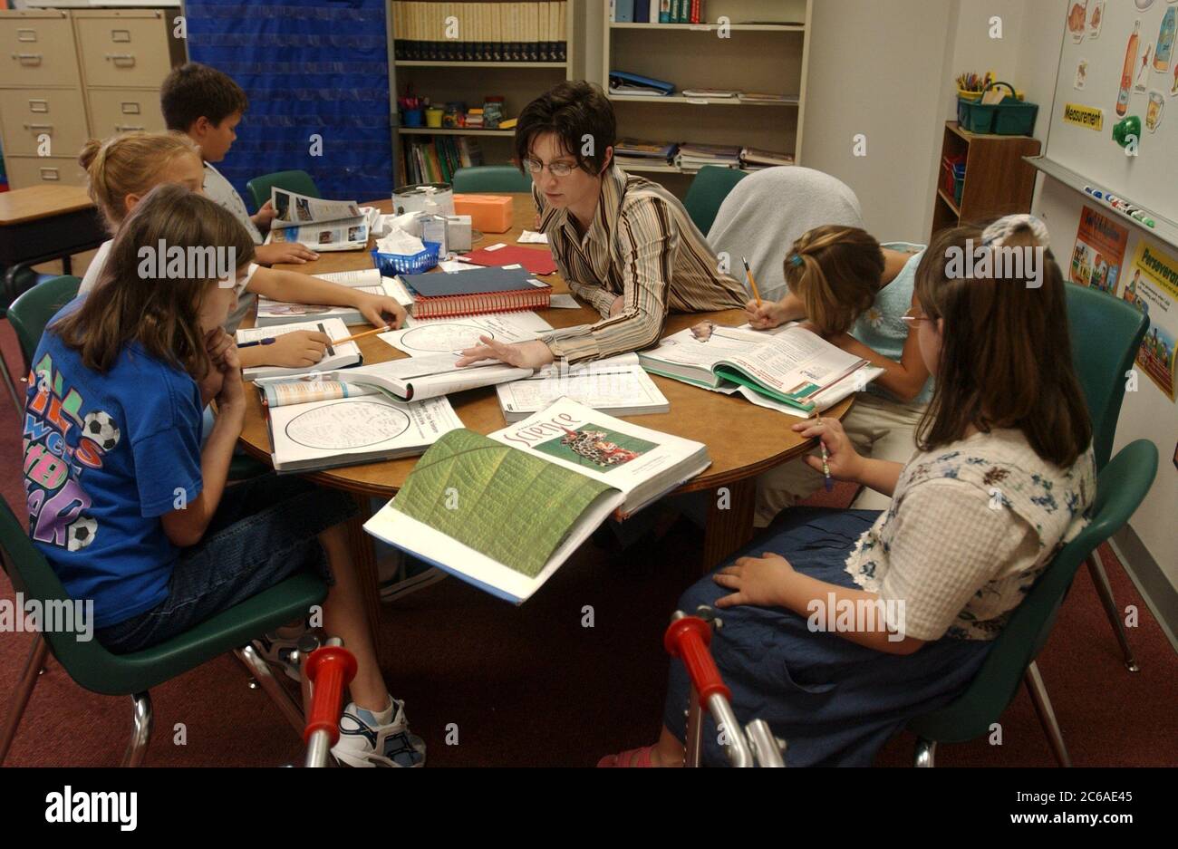 Gun Barrel City, Texas September 9, 2003: A physically handicapped girl (right) with cerebral palsy who uses a walker sits with classmates at a table with their teacher during a science lesson in their fifth-grade public school classroom. The school mainstreams its disabled students, placing them with normally abled students in all school settings.  MODEL RELEASE SP70 (girl with walker), others not released. ©Bob Daemmrich Stock Photo