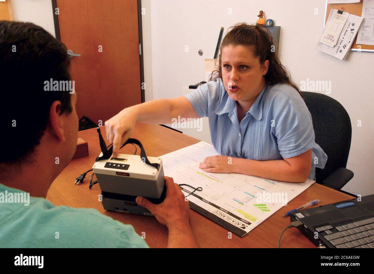 Austin, Texas USA: Female county parole officer meets with a parolee and explains Global Positioning System (GPS) monitoring devices that parolee wears for constant monitoring. Models Released .© Bob Daemmrich Stock Photo