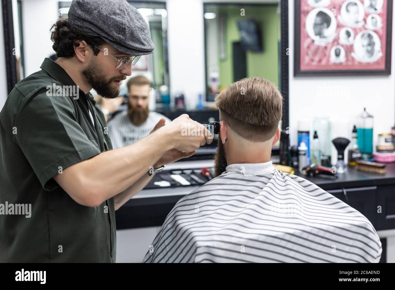 The hands of young barber making haircut to attractive man in ...