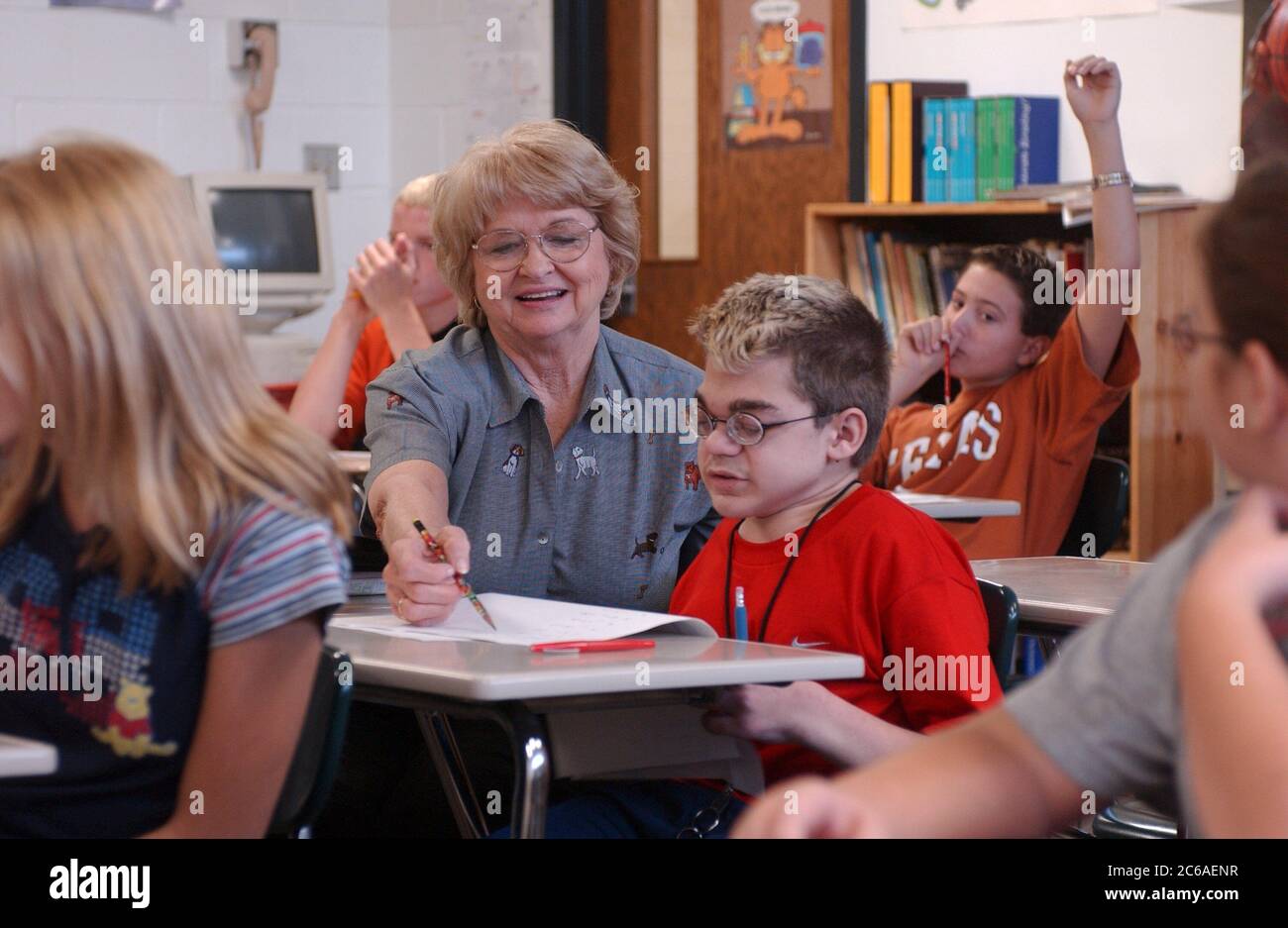 Mabank, Texas September 10, 2003: 12-year-old boy with Hurler Syndrome, with a full-time aide, writes in 7th grade CMC English. He is mainstreamed into a regular classroom. Model Release SP-73 (boy student in red) SP-74 (aide) other teacher SP-69.  ©Bob Daemmrich Stock Photo