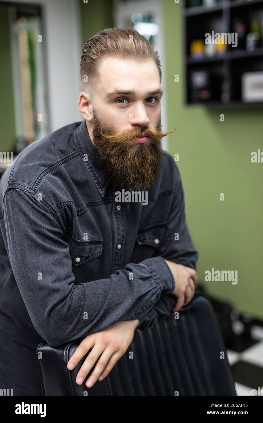 It is time for grooming. Handsome young bearded man looking at his