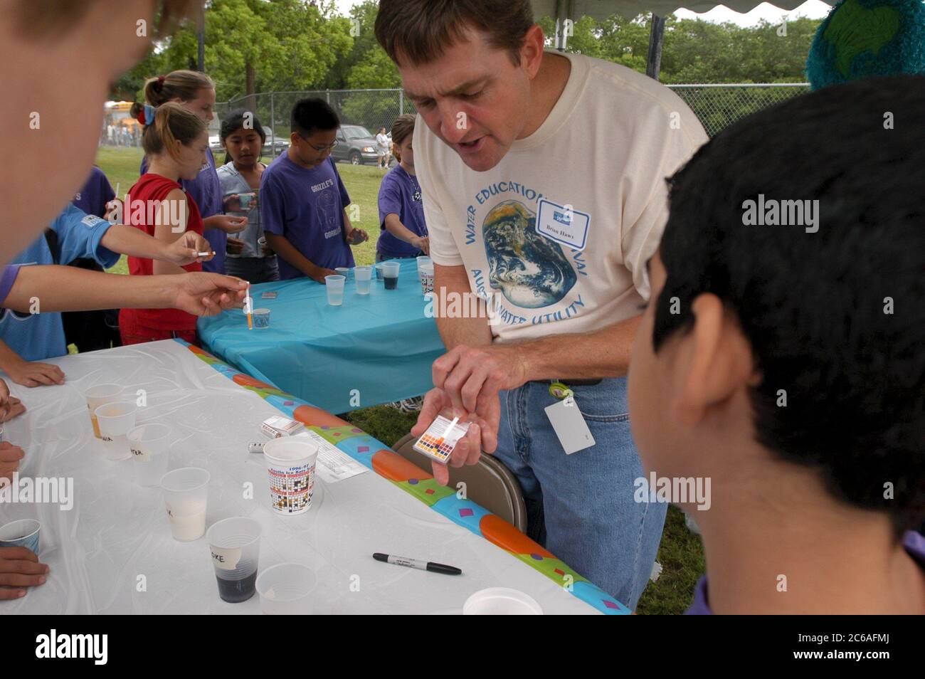 Austin Texas USA, April, 2004: Middle school students 6th and 7th grade learn about water and wastewater issues at City of Austin-sponsored Blue Thumb outdoor science event. Male instructor shows students how to test the pH of various liquids by using litmus paper. ©Bob Daemmrich Stock Photo