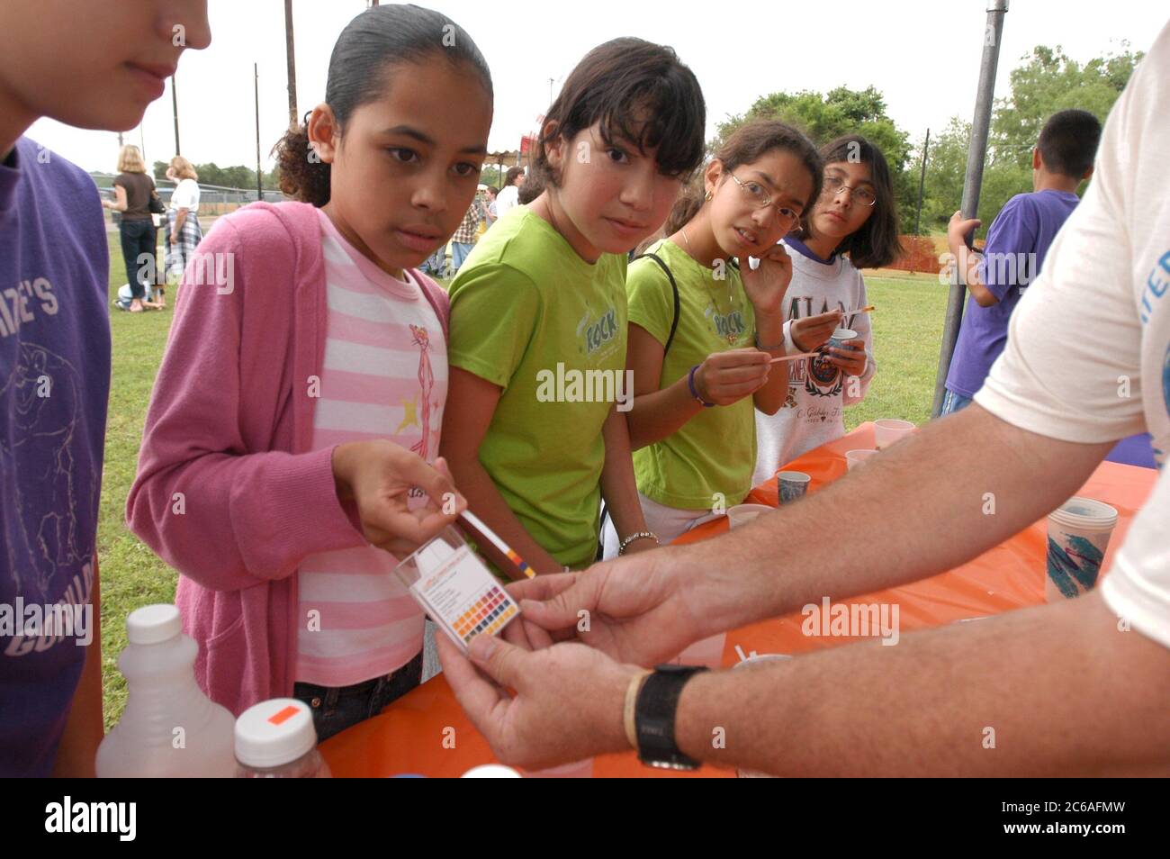 Austin Texas USA, April, 2004: Middle school students 6th and 7th grade learn about water and wastewater issues at City of Austin-sponsored Blue Thumb outdoor science event. Hispanic students test the pH of various liquids by using litmus paper. ©Bob Daemmrich Stock Photo