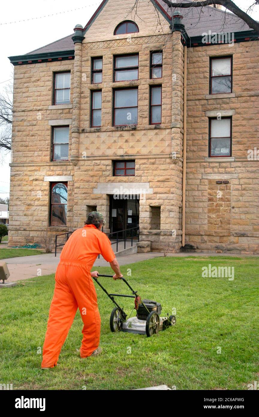 Brady, Texas, March 2004: Work-release prisoner mowing the lawn outside the McCulloch County Courthouse. ©Bob Daemmrich Stock Photo
