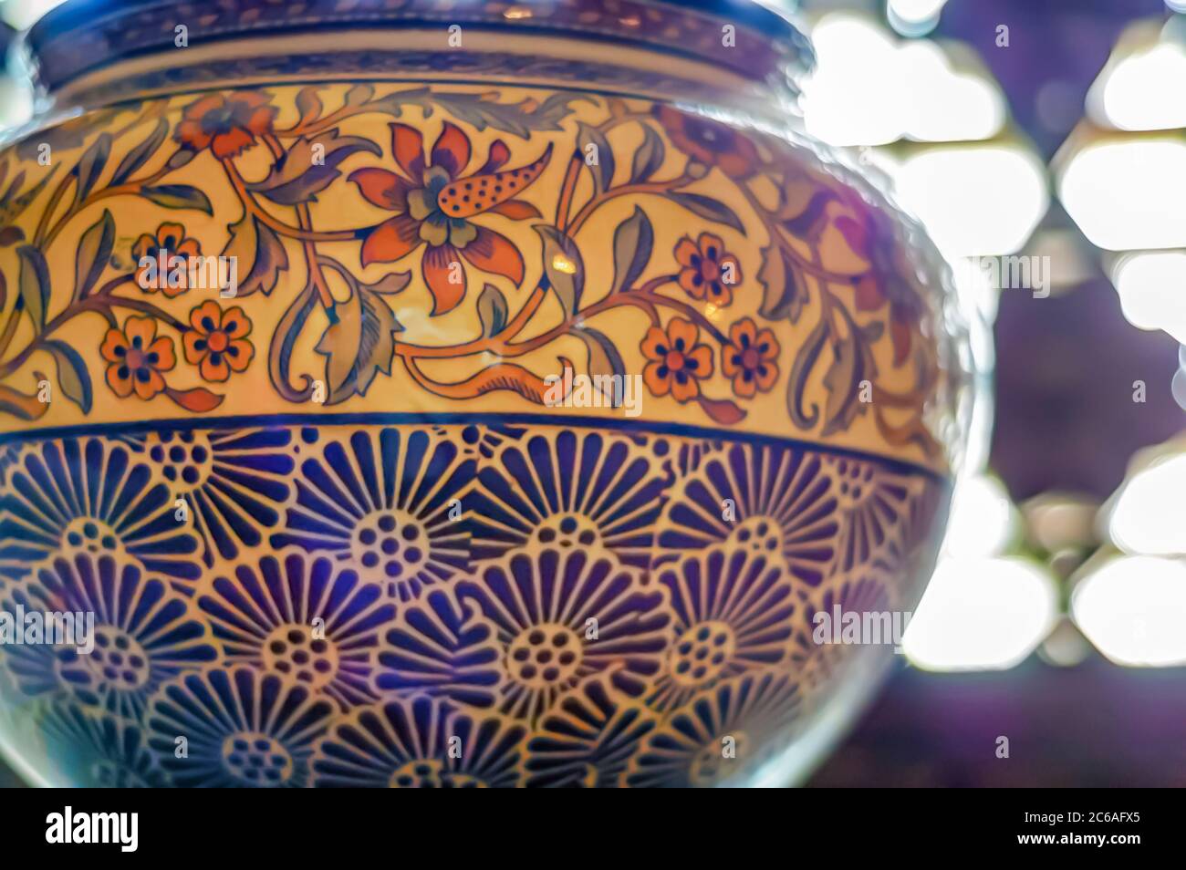 An antique ceramic vase sitting on a ledge adjacent to a window at the