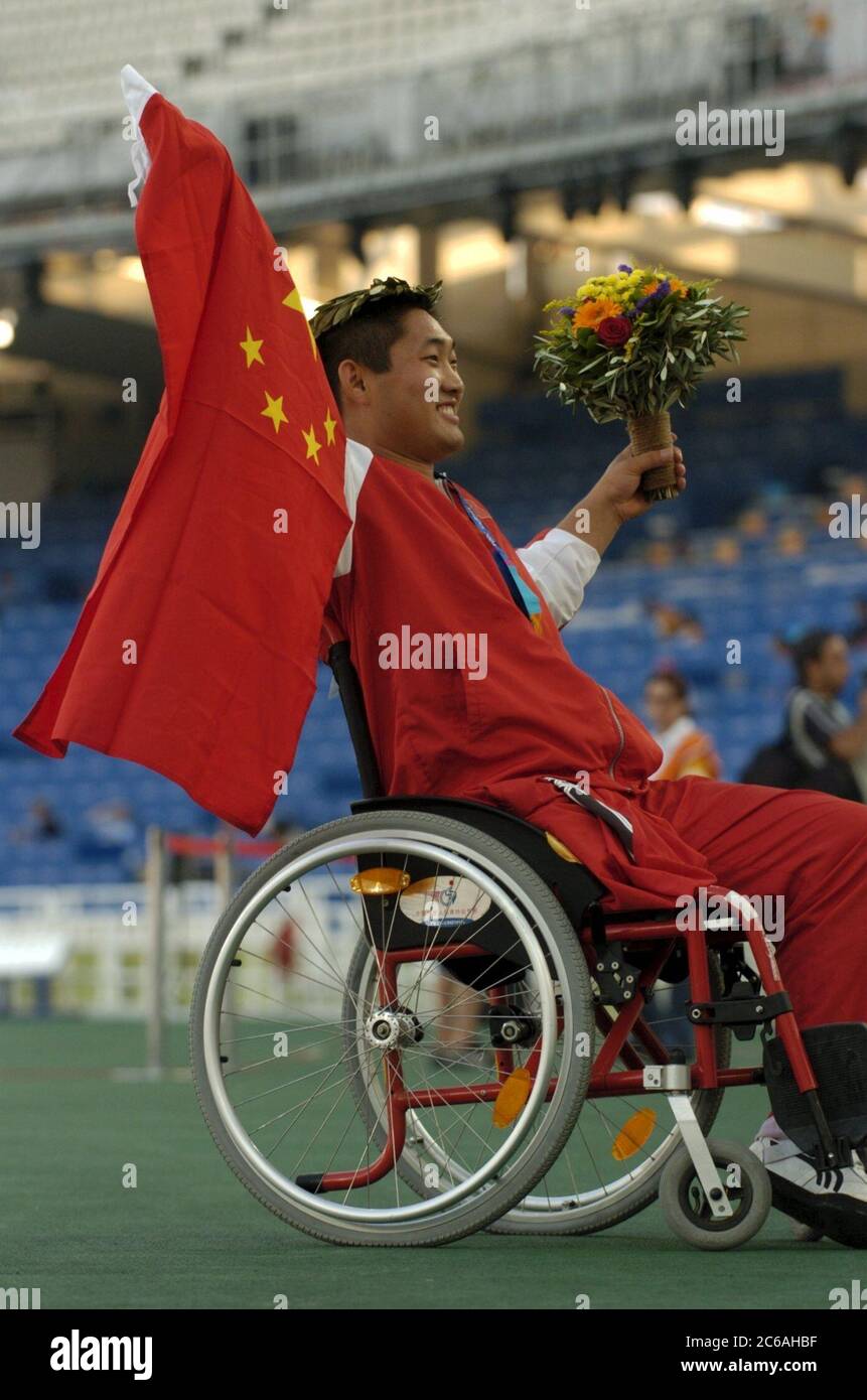 Athens, Greece 23SEP04: Paralympic Games  Chinese high jumper Bin Hou lifts the Chinese flag as he acknowledges cheers from the crowd during his gold medal ceremony at the Paralympic Games athletics competition in Olympic Stadium. ©Bob Daemmrich Stock Photo
