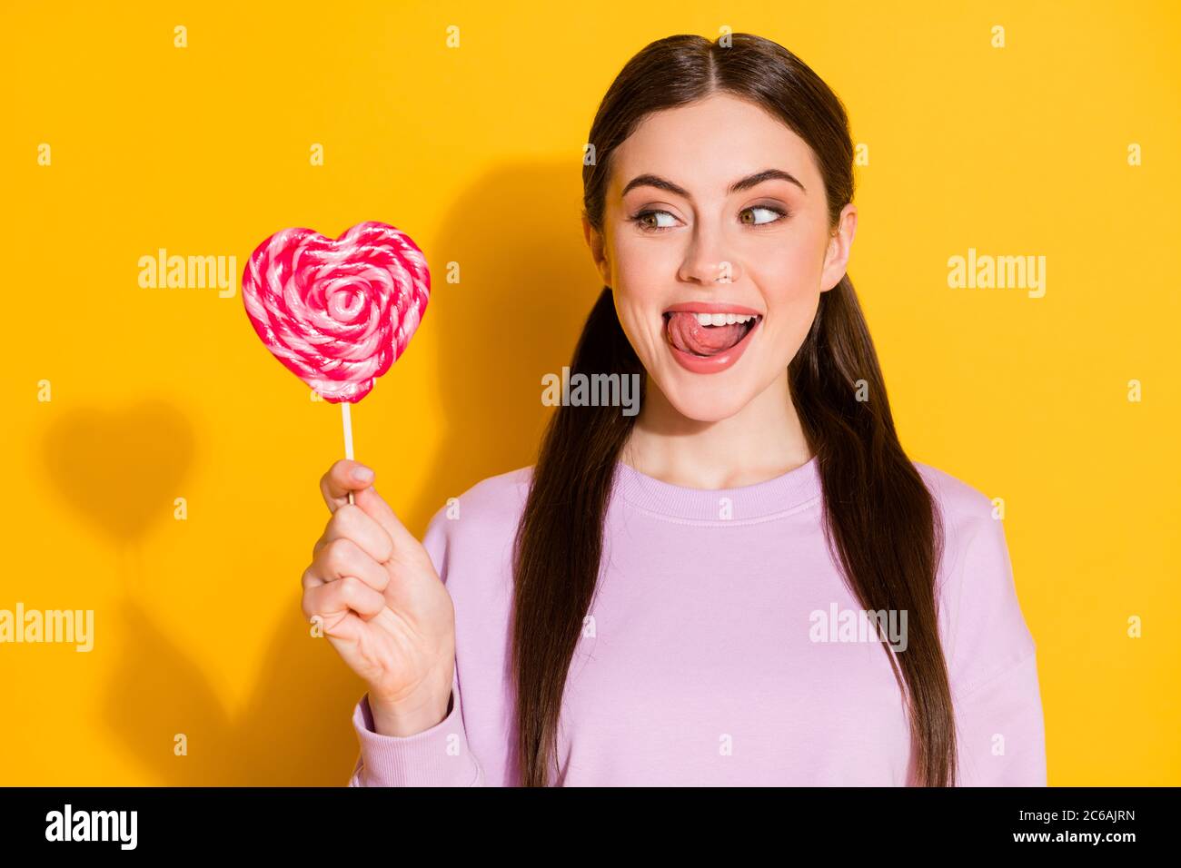 Close-up portrait of her she nice attractive lovely pretty cute funky girlish cheerful cheery girl licking sugary candy isolated over bright vivid Stock Photo