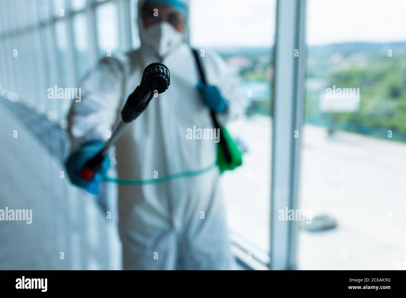 Coronavirus Pandemic. A disinfector in a protective suit and mask sprays disinfectants inoffice. Protection against COVID-19 disease. Stock Photo