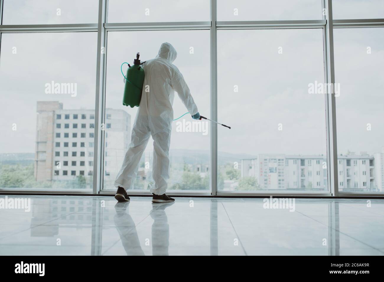 Man disinfector cleaning office space and window before work on corona virus pandamia. Stock Photo