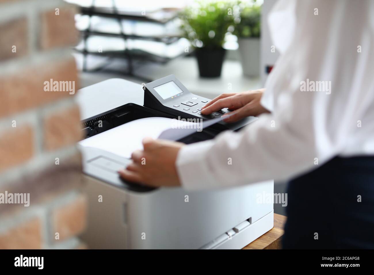 Woman in office prints documents on printer Stock Photo