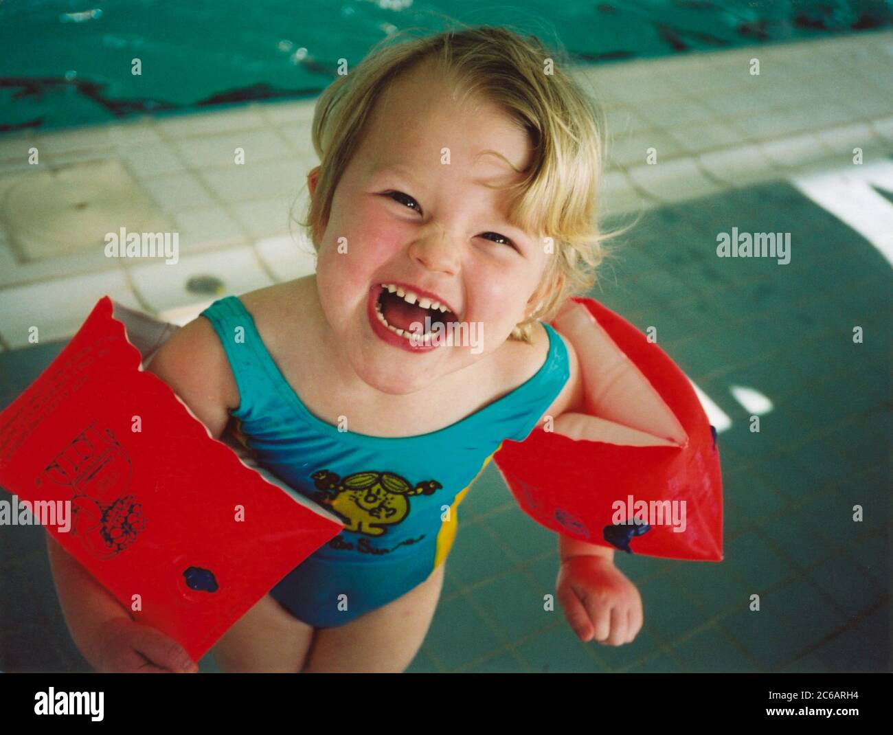 Three year old girl having a swimming lesson wearing armbands Stock