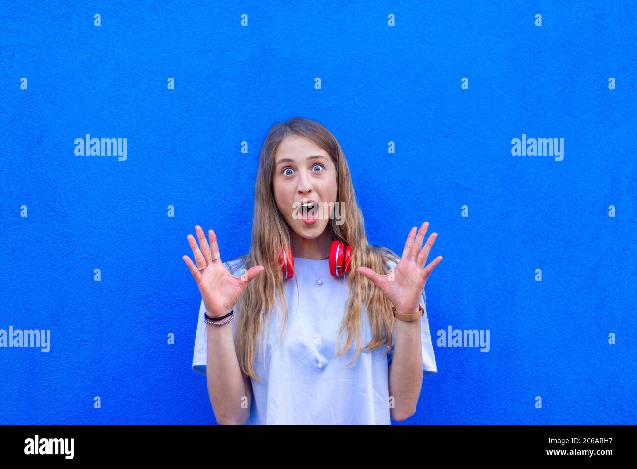 portrait of young girl with surprised expression and colored background - surprise expression of young woman with blue background Stock Photo