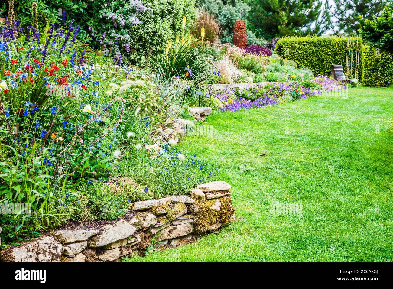 Terraced herbaceous borders in a sloping country garden. Stock Photo